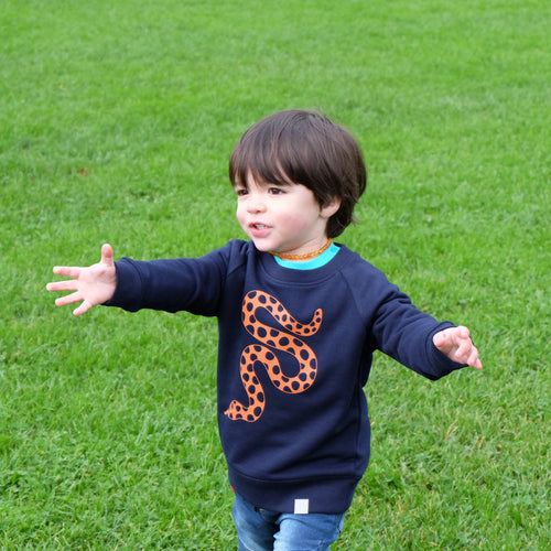 boy wears navy sweatshirt with orange snake on